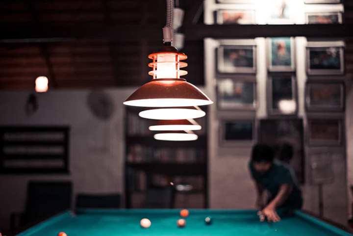 lights hanging over a green felt pool table