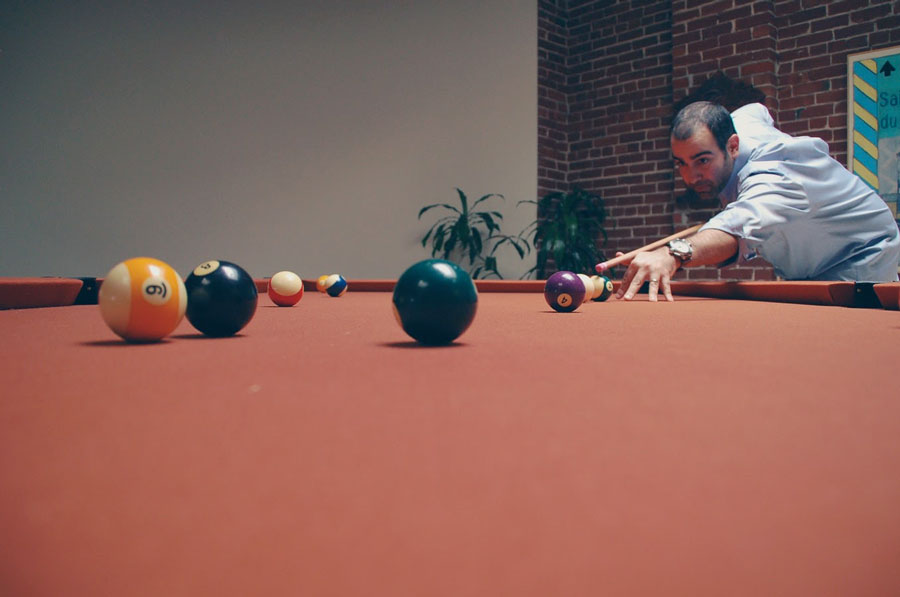 Man playing billiards near plants